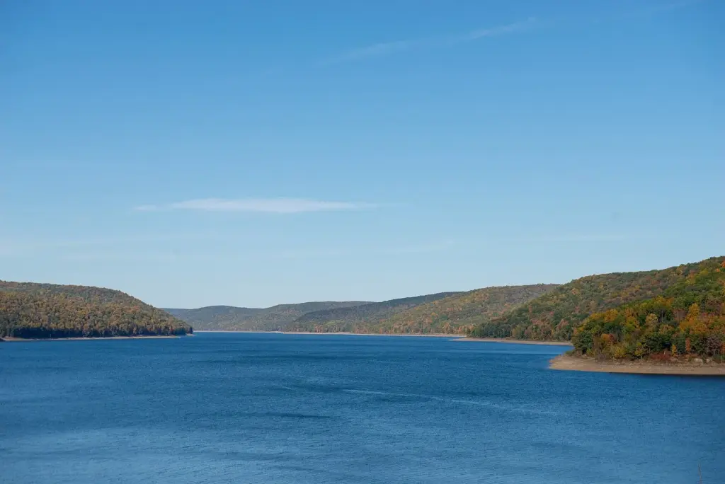 The Allegheny Reservoir under a blue sky, with autumn-colored hills along both shores