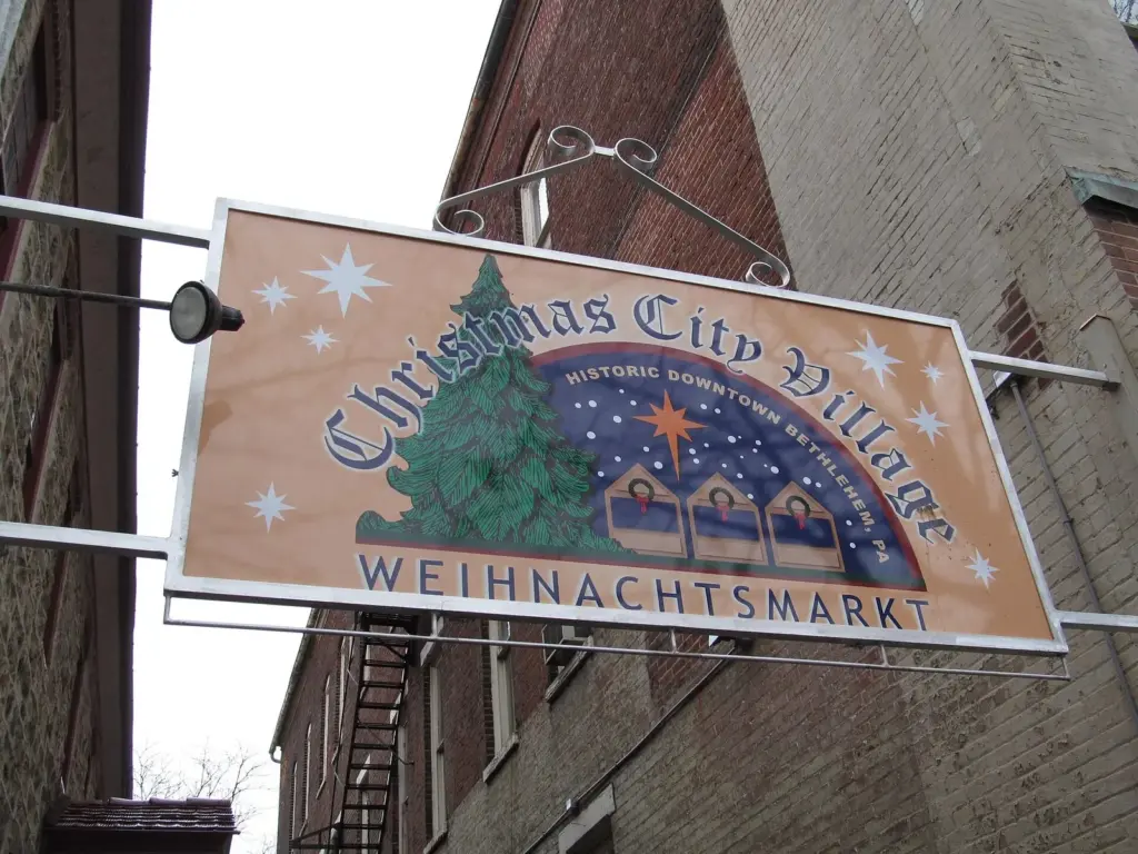 A painted sign for the Christmas City Village holiday market on a brick building in Bethlehem