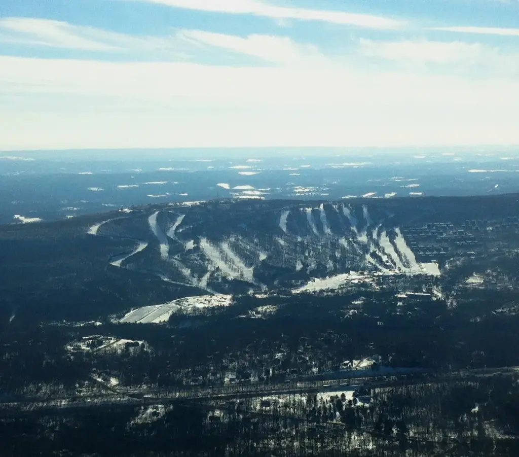 Aerial view of Camelback's white ski trails cut through the dark forest of the Poconos