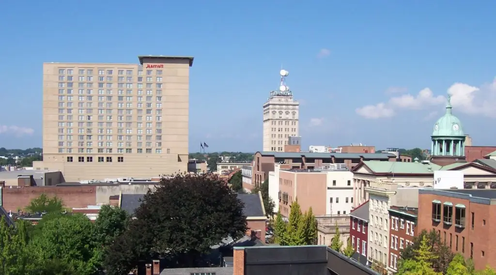 Downtown Lancaster's rooftops, church domes and tall hotel under a blue summer sky