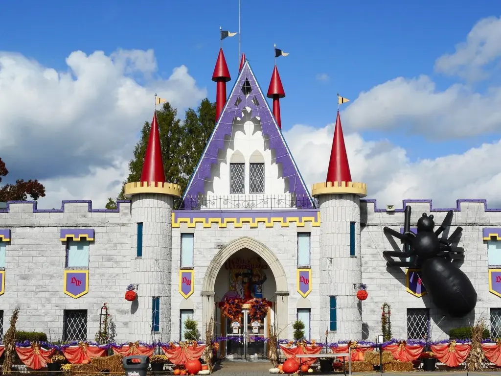 Dutch Wonderland's white castle entrance with red turrets, decorated with a giant spider for Halloween