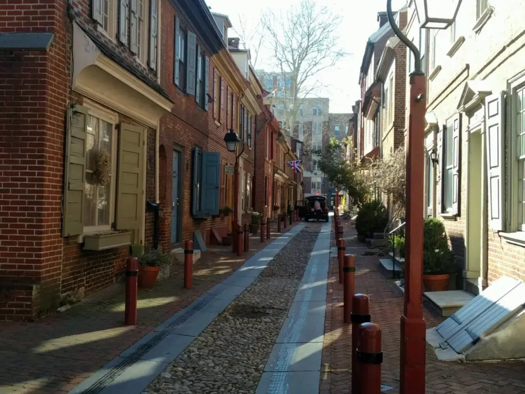 Colonial brick rowhouses with shutters lining the narrow cobbled lane of Elfreth's Alley