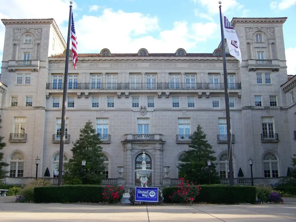 The pale stone front of the Hershey Theatre building with flags and a fountain