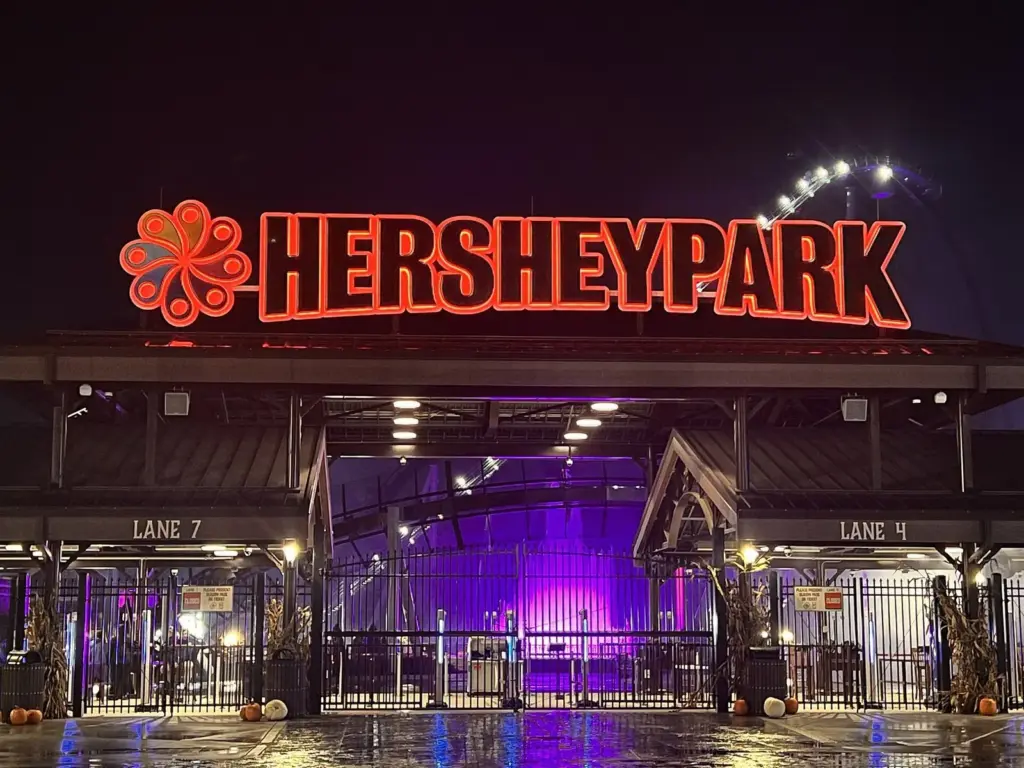 The glowing Hersheypark sign over the park's entrance gates at night