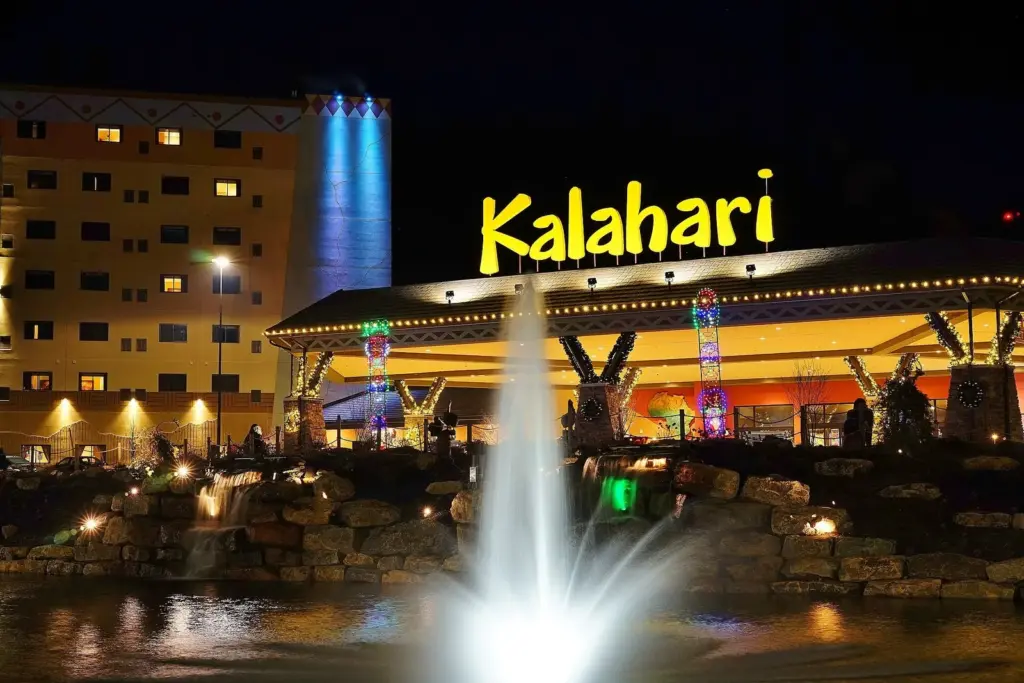 Kalahari Resorts Poconos lit up at night with its sign, entrance and a fountain