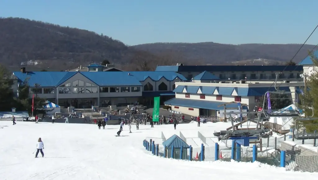 Skiers and a chairlift at the base of Liberty Mountain Resort in front of the lodge