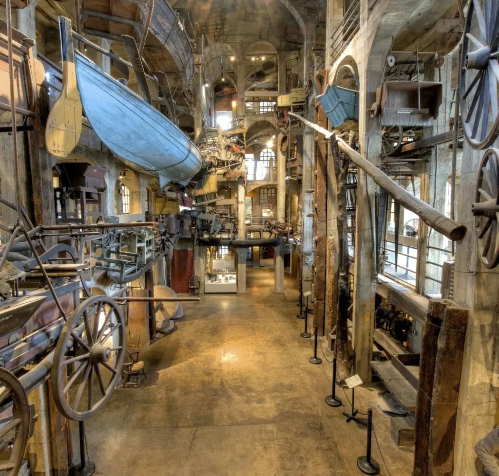 A whaleboat, wagons and other large objects hanging in the multi-story concrete atrium of the Mercer Museum