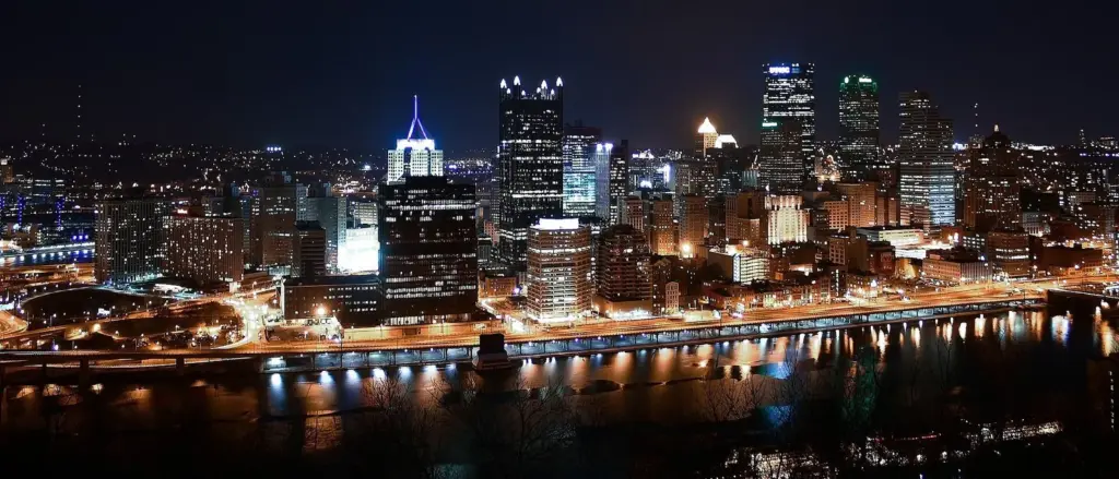 Downtown Pittsburgh's towers lit up at night above the Monongahela River, seen from Mount Washington