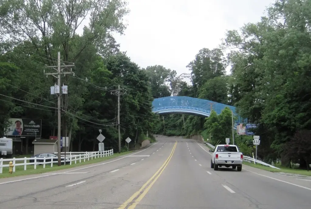 The blue Ravine Flyer II coaster bridge crossing over a two-lane road in Erie