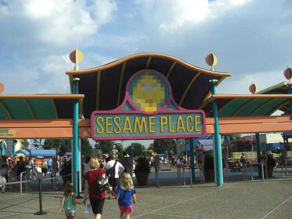 The colorful Sesame Place sign over the park's entrance plaza on a sunny day