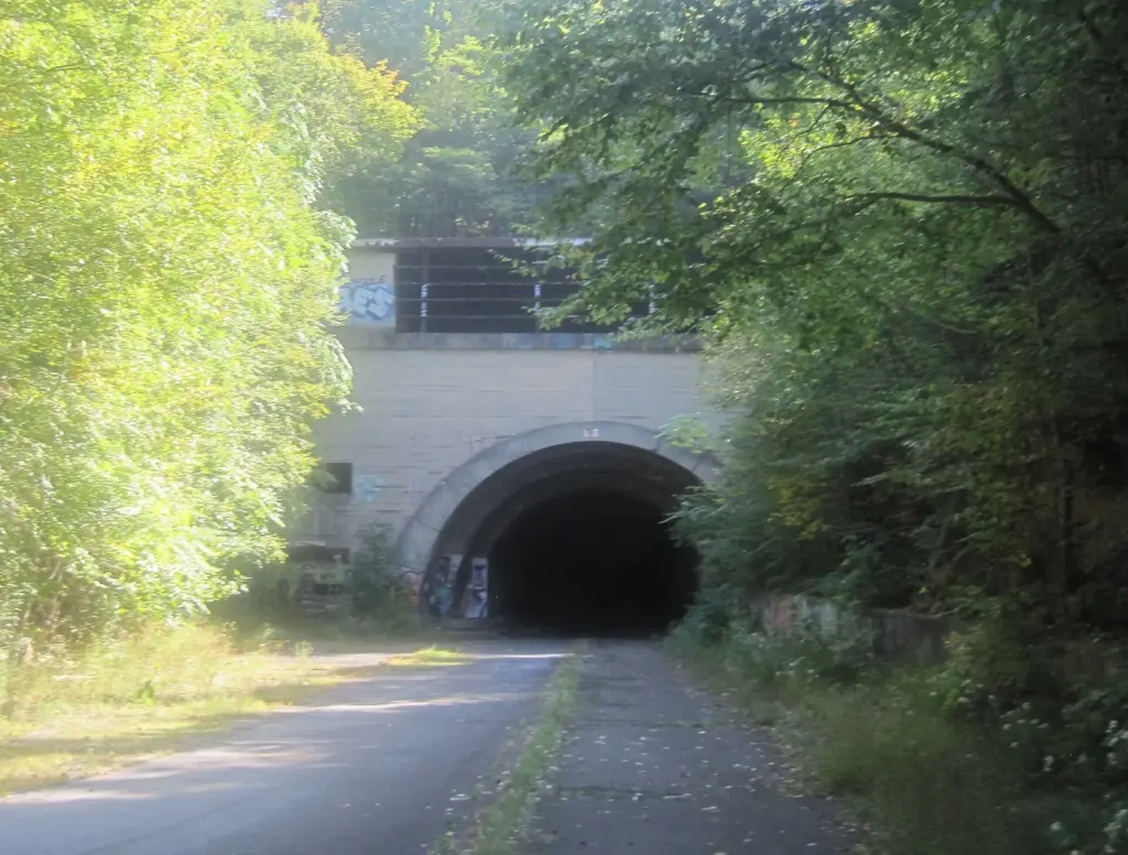 The concrete portal of Sideling Hill Tunnel with the old Turnpike roadway leading into it through the trees