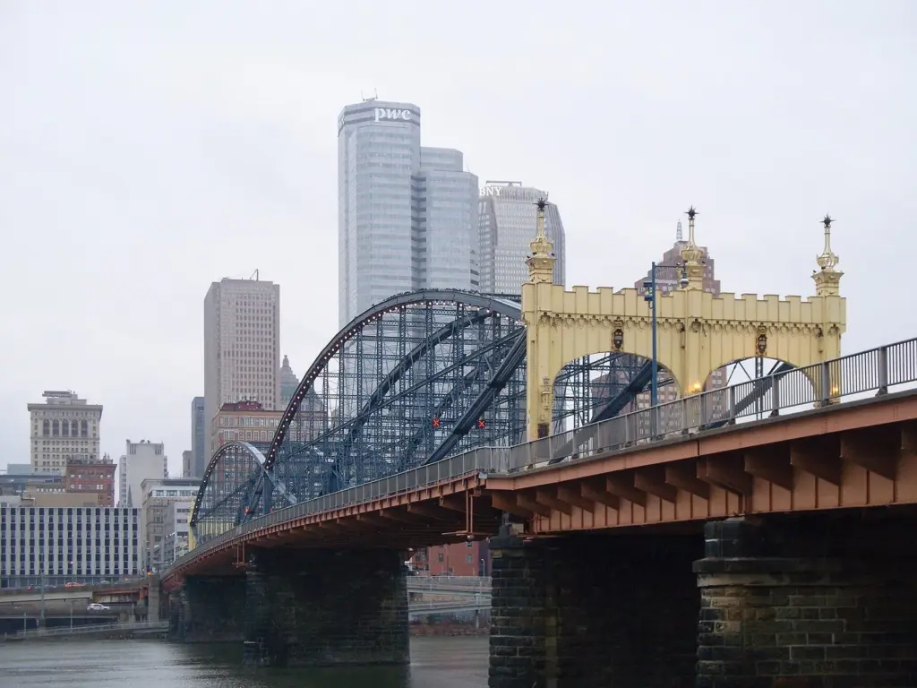 The blue lenticular trusses and yellow portal of the Smithfield Street Bridge with downtown towers behind