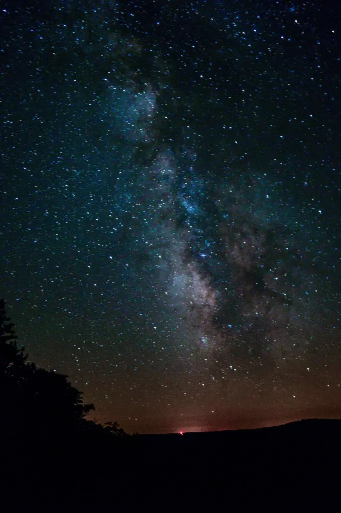 The Milky Way rising over a dark tree line at Cherry Springs State Park