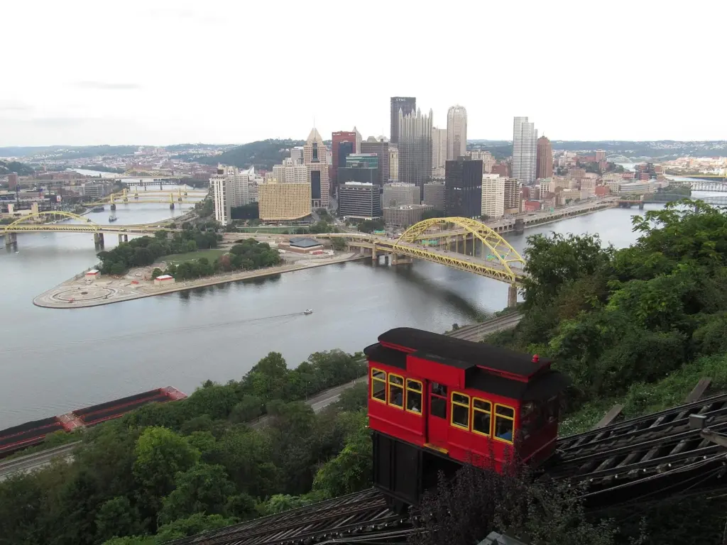 A red Duquesne Incline car above the rivers and downtown Pittsburgh skyline