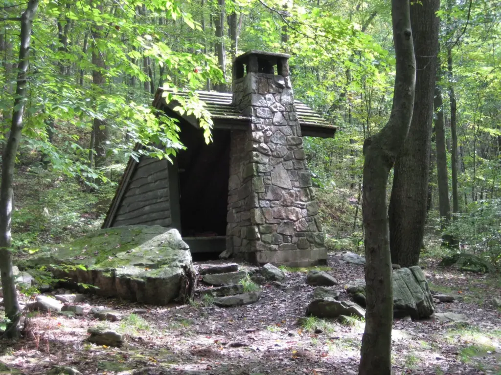 Wooden shelter with a stone chimney beside the Laurel Highlands Hiking Trail