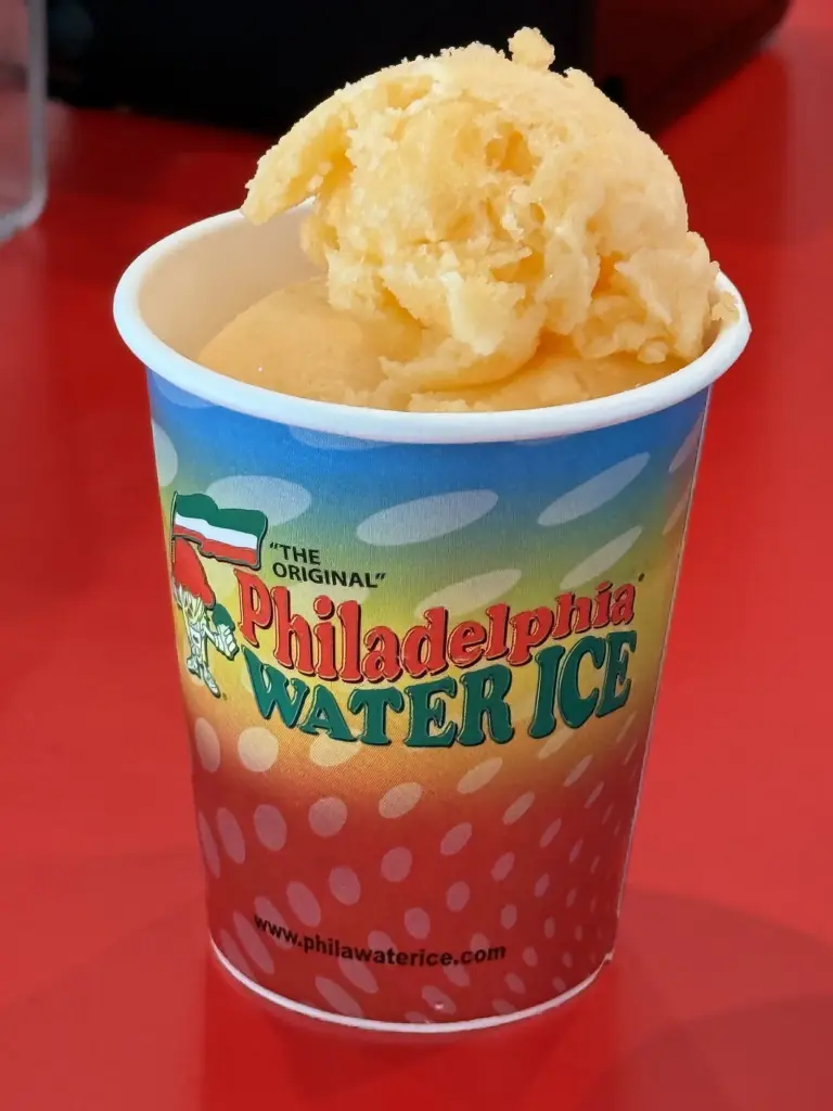 A cup of mango water ice in a printed paper cup